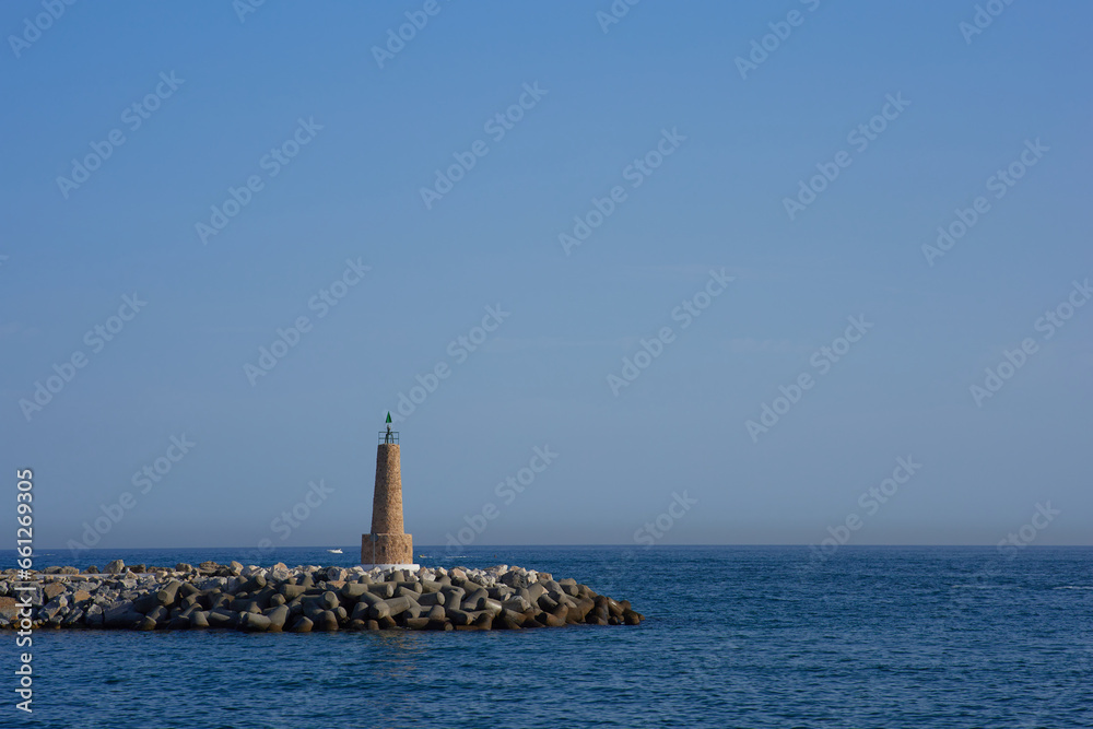 Lighthouse in the middle of the sea with blue sky background.