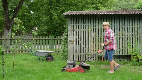 A gardener tends the green lawn around a small apple tree near the woodshed in late summer