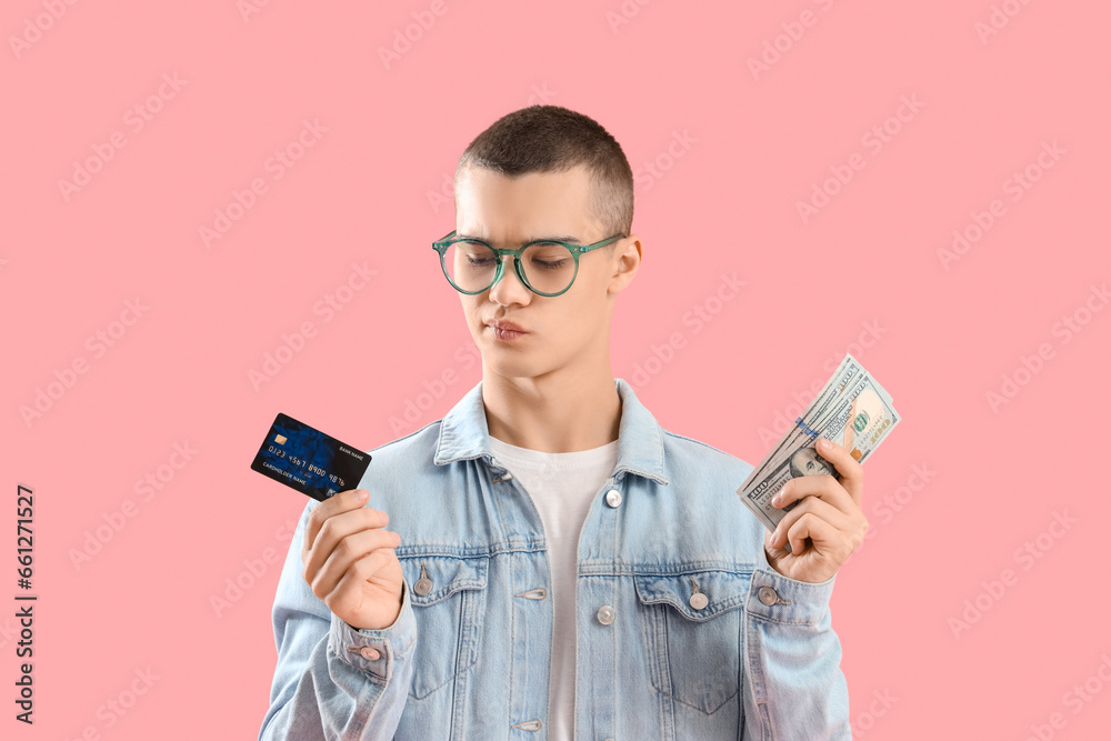 Thoughtful young man with credit card and dollar banknotes on pink background Thoughtful young man with credit card and dollar banknotes on pink background