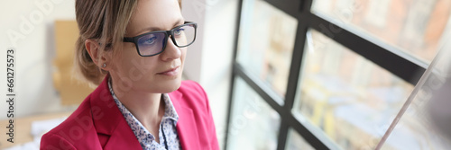 Focused woman in glasses writes strategy on whiteboard