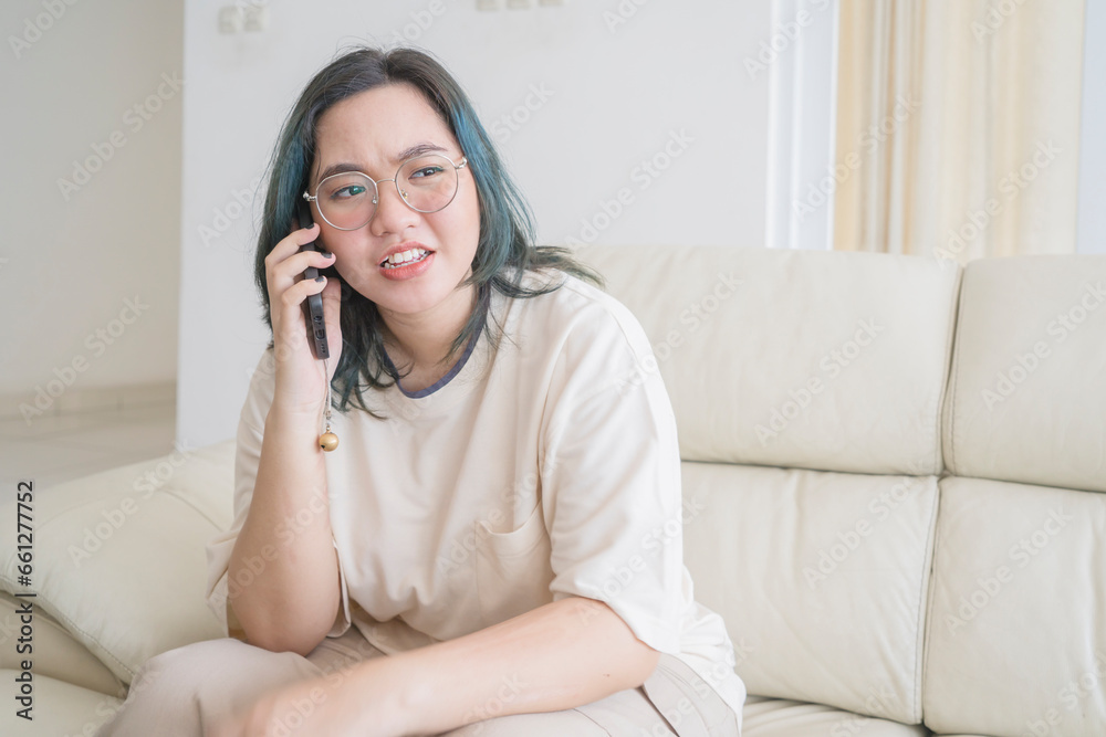 Asian woman talking on the phone while sitting on sofa a Asian woman talking on the phone while sitting on sofa a