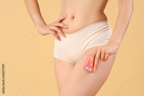Young woman with epilator on beige background, closeup