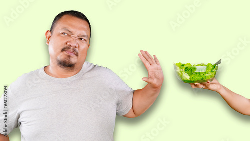 overweight asian guy refusing eating salad offered by his wife