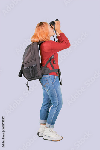 Young trendy photographer with red hair carrying camera backpack taking photos