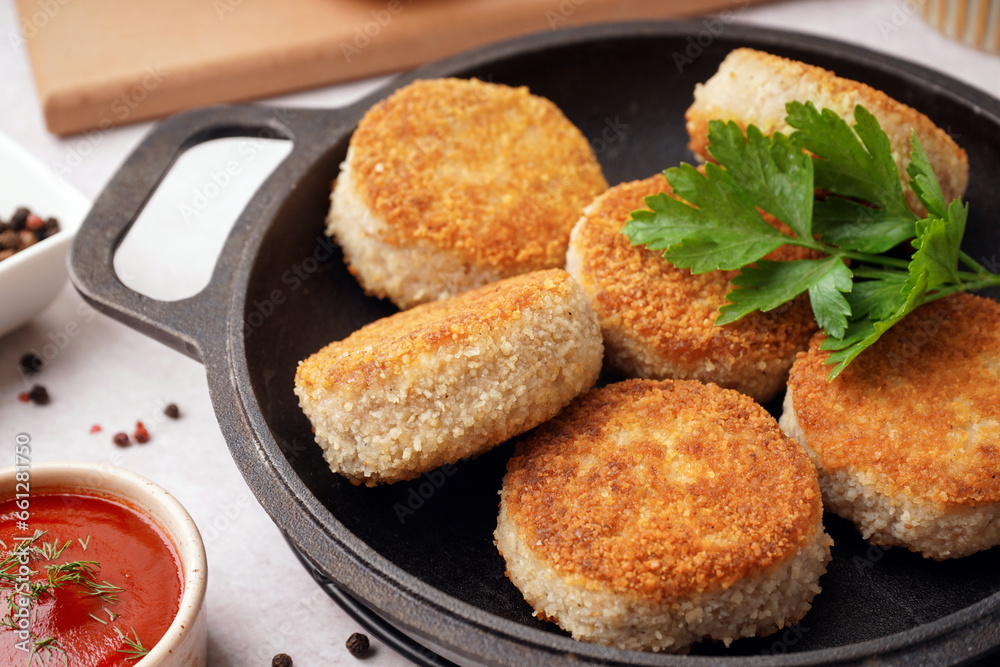 Frying pan with tasty meat cutlets and sauce on white background