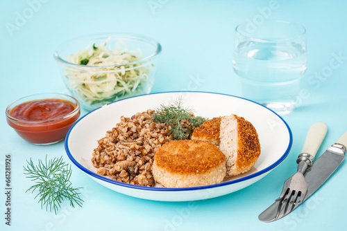 Plate of tasty meat cutlets with buckwheat and sauce on blue background