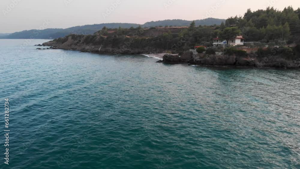 Aerial Drone over Aegean sea rocky beach at sunset clear waters
