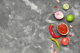 Bowl with tasty salsa sauce and ingredients on grey background
