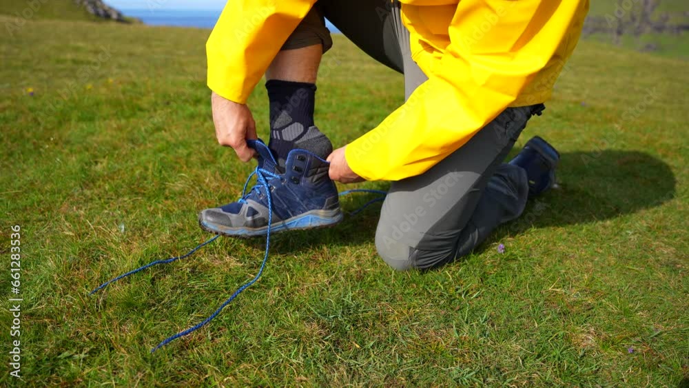Closeup of a male hiker kneeling and cleaning his sock to put a boot on Closeup of a male hiker kneeling and cleaning his sock to put a boot on