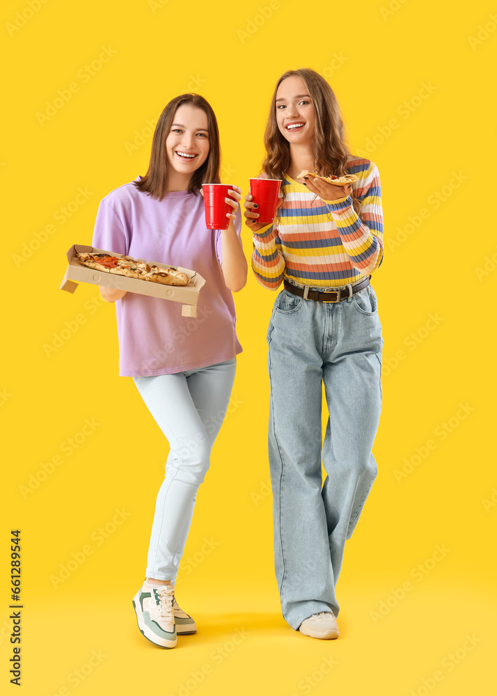 Female friends with tasty pizza and beer on yellow background Female friends with tasty pizza and beer on yellow background