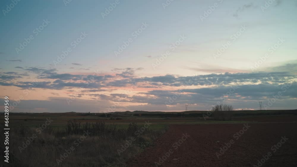 Vast rural field under a cloud-filled dusk sky with a motorway nearby Vast rural field under a cloud-filled dusk sky with a motorway nearby