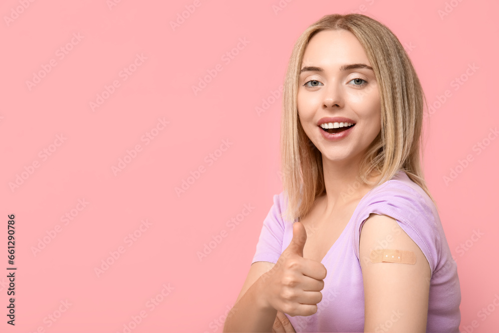 Young woman with medical patch on arm showing thumb-up against pink background. Vaccination concept Young woman with medical patch on arm showing thumb-up against pink background. Vaccination concept