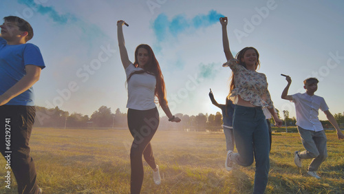 A group of friends spraying multi-colored smoke at sunset.