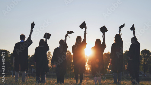 Silhouette of fresh graduates throwing their motarboard or trencher up in the air after their graduation. photo