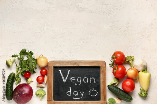 Board with text VEGAN DAY and fresh vegetables on white background