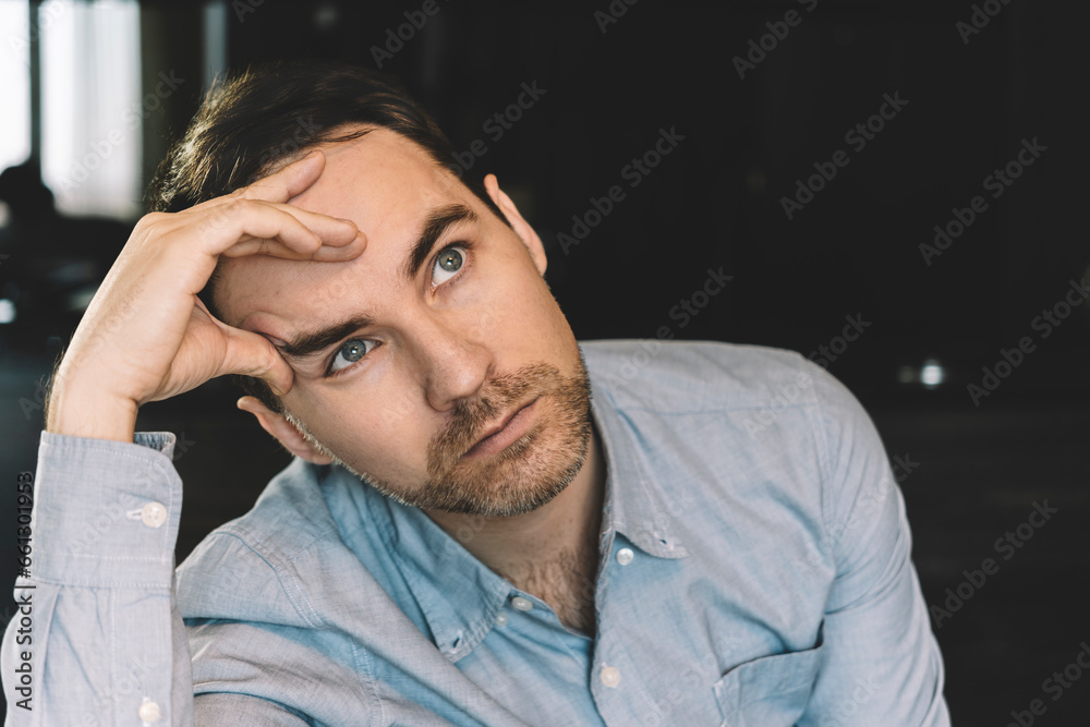 young man sits pensive and looks away holding his head with his hand. Thoughts and dreams concept young man sits pensive and looks away holding his head with his hand. Thoughts and dreams concept