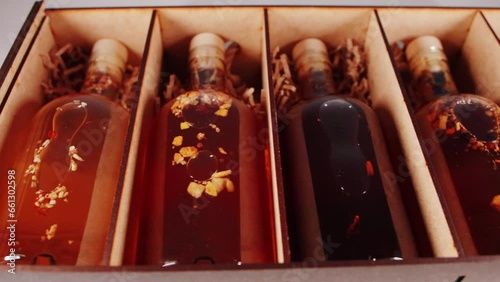 Herbal alcoholic tinctures in a wooden box, close-up. Elite collection alcohol brandy and cognac. Movement from the slider, natural photo