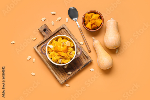 Pot of tasty millet porridge with pumpkin and ingredients on orange background