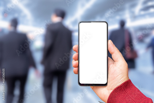 Mockup blank white screen of smartphone, male hand holding modern black cellphone with template screen for your logo or design,business office background.