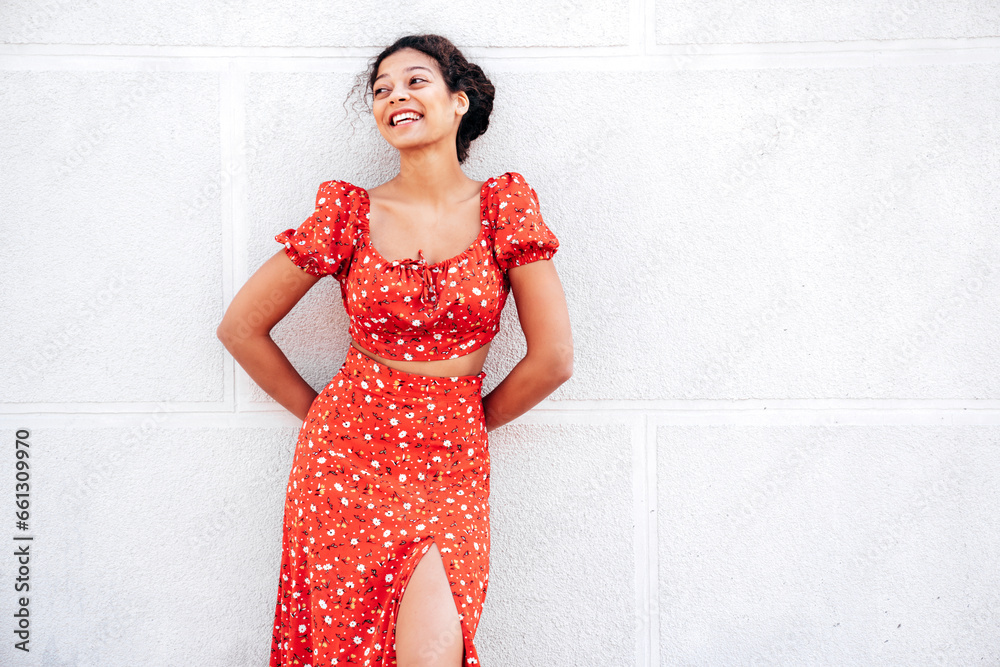 Young beautiful smiling hipster woman in trendy summer red dress. Carefree woman posing in the street near wall. Positive model outdoors in at sunny day. Cheerful and happy Young beautiful smiling hipster woman in trendy summer red dress. Carefree woman posing in the street near wall. Positive model outdoors in at sunny day. Cheerful and happy