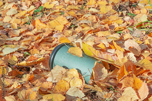 A used paper coffee cup lies in the autumn forest. Environmental pollution from household waste