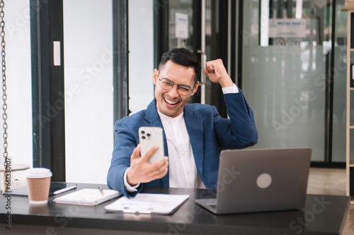Young handsome man typing on tablet and laptop while sitting at the working wooden table modern office.