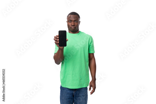 a young american guy dressed in a mint t-shirt holds a smartphone with the screen facing forward