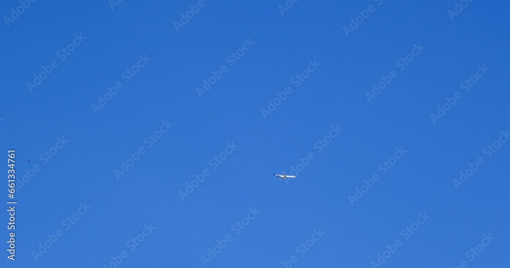 Airplane flying on deep blue sky with chemical direction trails, view from a distance Airplane flying on deep blue sky with chemical direction trails, view from a distance