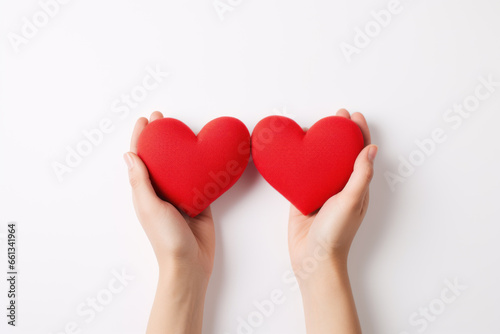 Hands holding two red heart shapes.