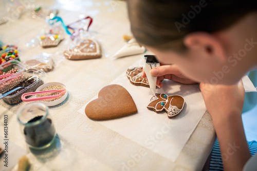 Close-up of a young girl decorating gingerbread cookies with icing.