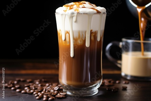 filling a large, clear glass with layers of hot chocolate and cream