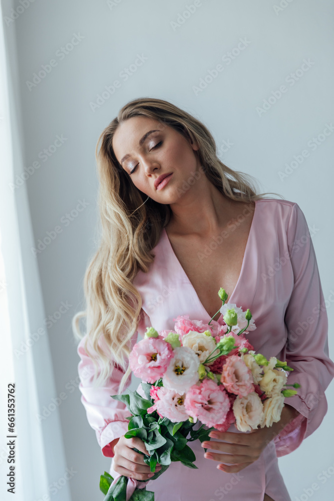 Beautiful woman in pink dress with flowers in the room for a holiday
