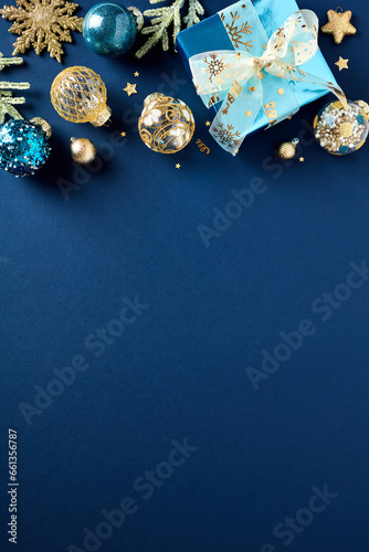 Christmas poster, party invitation card template. Flat lay glistening gold and blue balls, gift box with ribbon bow, fir branches on dark blue background. Top view. Flat lay.