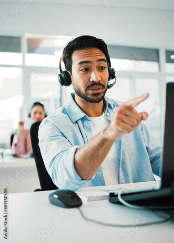 Asian man, call center and pointing in customer service, support or telemarketing at office. Businessman, consultant or agent with headphones in contact us for online advice or help at workplace
