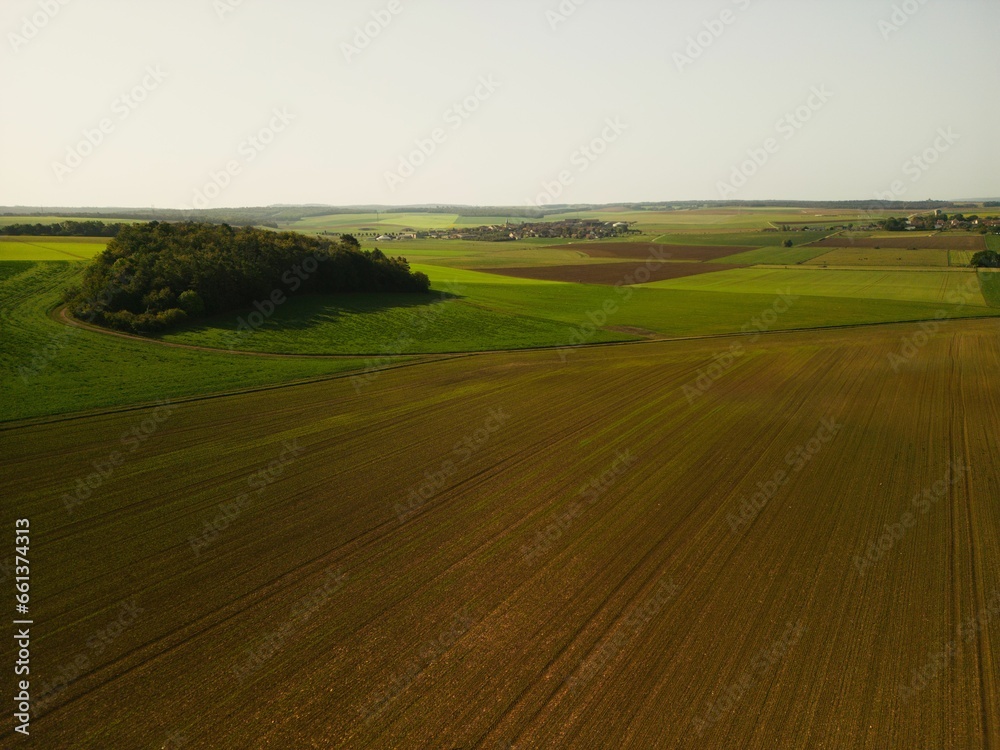 a plowed field in the middle of spring, with farmland visible