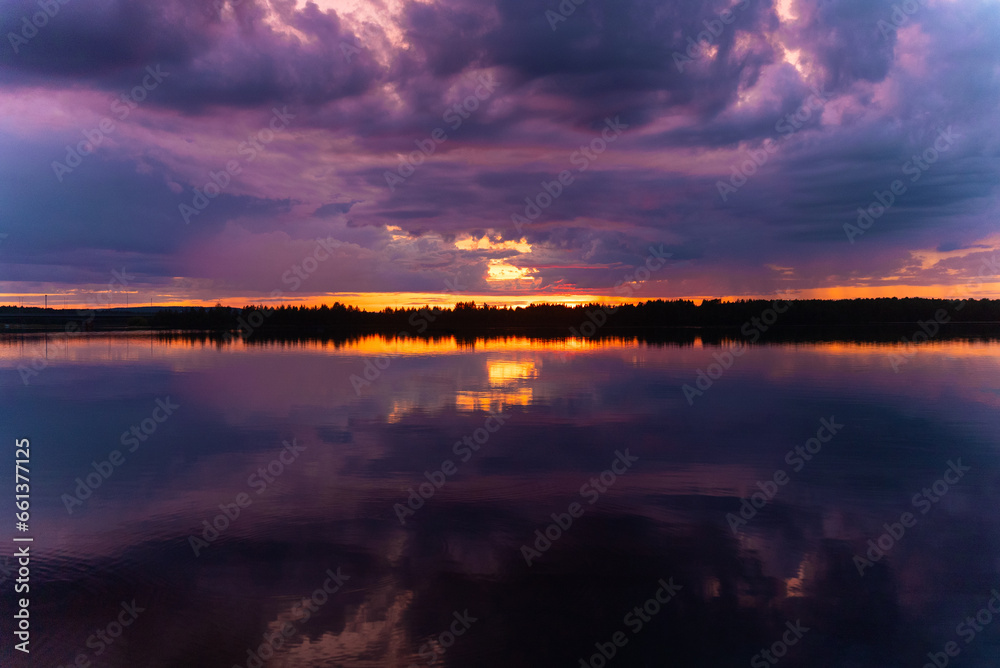 Multicolored dark sunset on the river in Rovaniemi in Finland. Polar day. View of Lapland. Reflection in water. Suomi. Journey north. Northern beauty, traveling to the Arctic Circle 