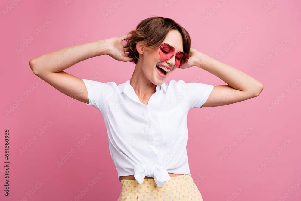 Portrait of gorgeous woman with short hairstyle wear stylish blouse in sunglass hands on head dancing isolated on pink color background Portrait of gorgeous woman with short hairstyle wear stylish blouse in sunglass hands on head dancing isolated on pink color background
