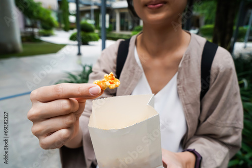 Woman holding popcorn cheese in a paper bag  in the hand
