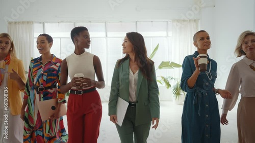 Cinematic footage of a multiethnic group of women managing new projects in a start up business. Female colleagues working as a team in the office wearing elegant colored diverse outfits