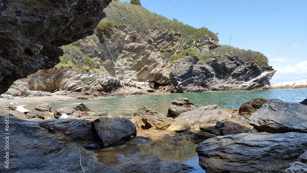 The rugged shoreline is filled with jagged rocks, contrasting with the crystal-clear waters that stretch out endlessly. The rugged shoreline is filled with jagged rocks, contrasting with the crystal-clear waters that stretch out endlessly.
