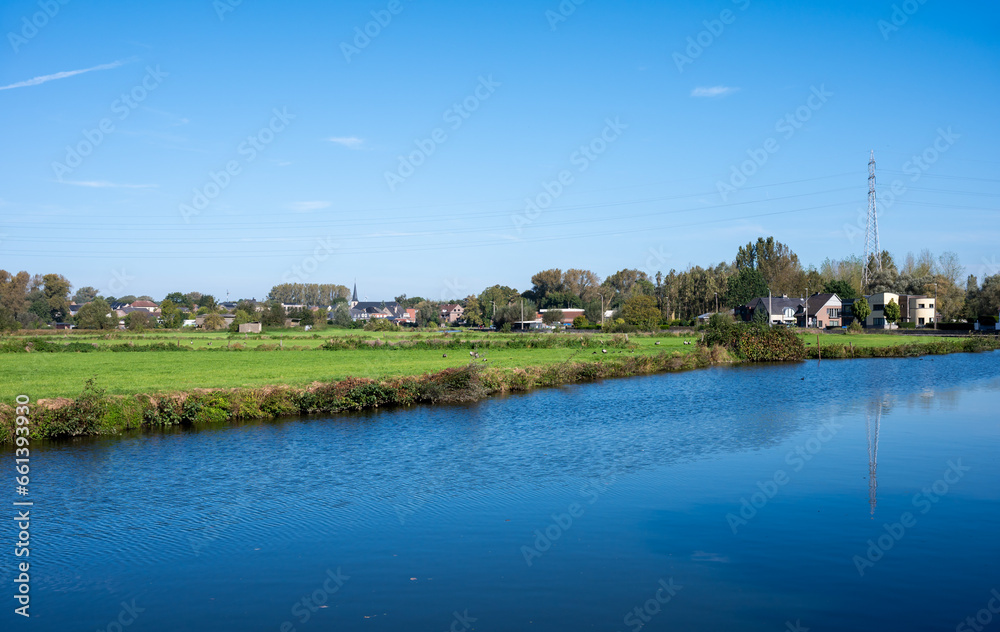 Obraz premium Houses and nature reflecting in the water of the river Dender, Ninove, Flemish Region, Belgium, October