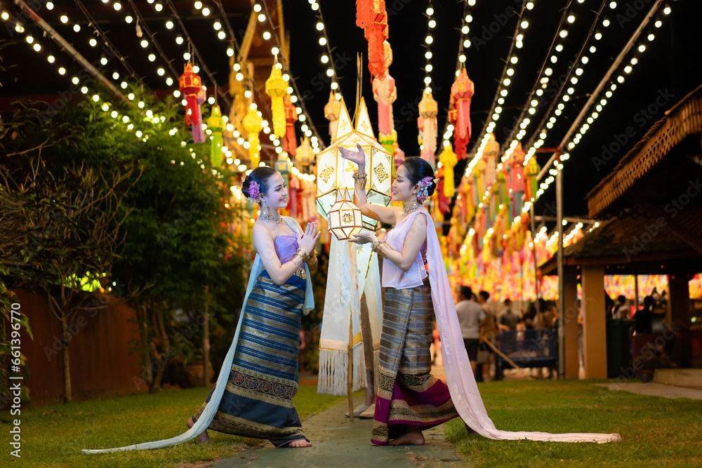 Φωτογραφία Pretty Asian women wearing beautiful Thai traditional dress in Hundred Thousand Lantern Festival or Yi Peng Festival for worship at Phra That Hariphunchai temple in Lamphun, Thailand