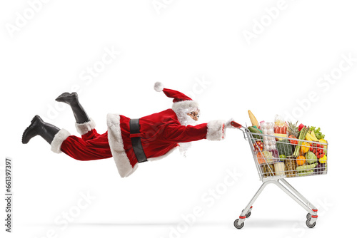 Santa claus flaying and holding a shopping cart with food © Ljupco Smokovski