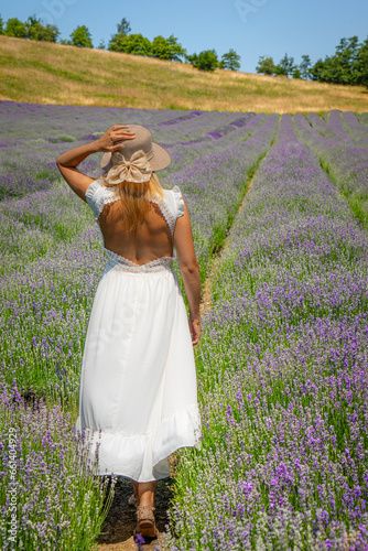 Girl with a white dress walking in a lavender field in summer time