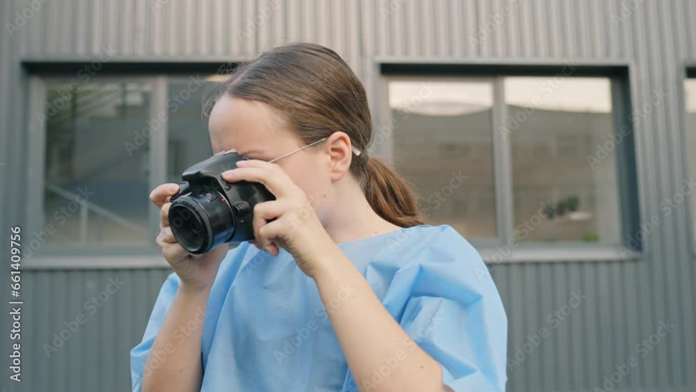 Young woman in scrub takes pictures using digital camera