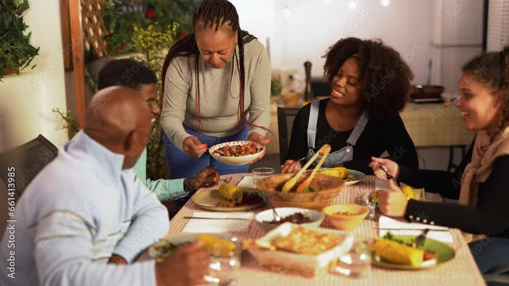 Happy african family eating dinner together at house terrace - Mother serving healthy vegetable food Happy african family eating dinner together at house terrace - Mother serving healthy vegetable food