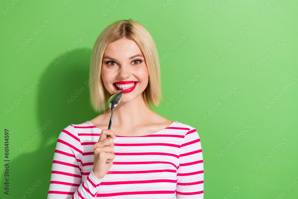 Photo of hungry funky gorgeous woman with bob hairstyle wear striped shirt biting spoon wait for food isolated on green color background Photo of hungry funky gorgeous woman with bob hairstyle wear striped shirt biting spoon wait for food isolated on green color background