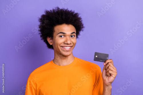 Portrait of nice cheerful person toothy smile hand hold plastic debit card isolated on purple color background