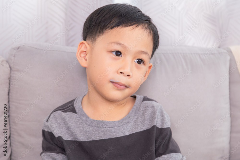 Close-up Asian preschool boy with milk mustache smile at unrecognizable mother sitting on sofa at home, young kid happy hold and drinking a clear glass full of dairy milk, healthy children's lifestyle Close-up Asian preschool boy with milk mustache smile at unrecognizable mother sitting on sofa at home, young kid happy hold and drinking a clear glass full of dairy milk, healthy children's lifestyle