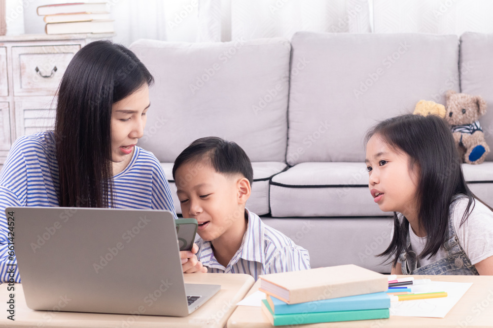Asian single mother teaching homework for two kids at home, homeschool learning lifestyle use modern technology laptop or watching lesson and participating online with teacher, multitasking motherhood Asian single mother teaching homework for two kids at home, homeschool learning lifestyle use modern technology laptop or watching lesson and participating online with teacher, multitasking motherhood